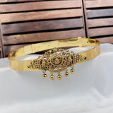 Gold belt with intricate design and hanging elements on a white surface with wooden background