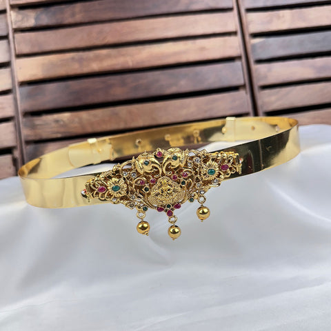 Gold bracelet with intricate designs and gemstones on a white surface with wooden background