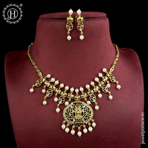 A gold-plated brass temple necklace set with intricate detailing and AD stones, displayed on a mannequin neck.
