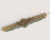 Decorative bracelet with gold and green beads on a light gray background