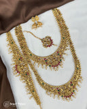 Gold necklace with red and green gemstones on a white and brown fabric background, brand 'Jewel Palace' visible.