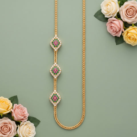 A gold chain necklace with three ornate diamond-shaped pendants, each decorated with small white stones and a central pink and green floral motif, arranged on a muted green background with decorative roses in the corners.