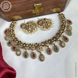 A gold-plated traditional Indian necklace set with matte finish and embellished with kemp stones, displayed on a wooden box.