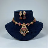 Jewelry set with necklace and earrings on a dark blue stand against a light gray background