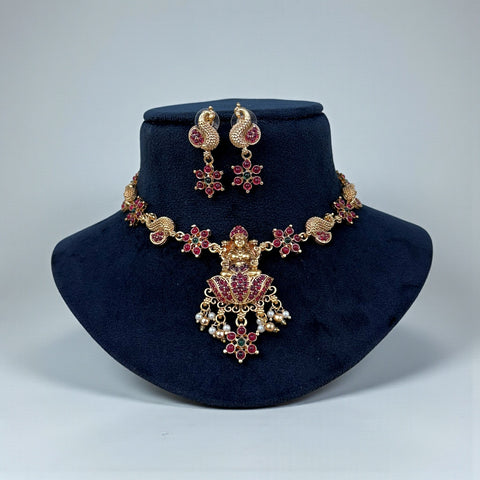 Jewelry set with necklace and earrings on a dark blue stand against a light gray background