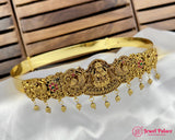 Gold headband with intricate designs and dangling beads on a white fabric background