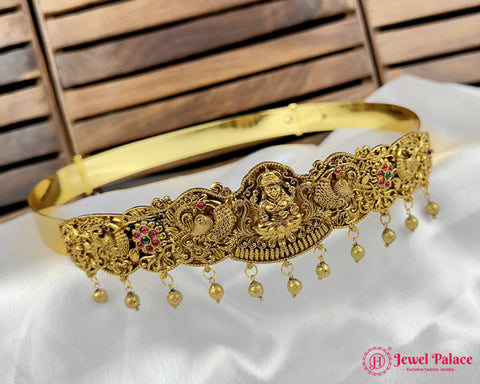 Gold headband with intricate designs and dangling beads on a white fabric background