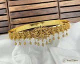 Gold necklace with hanging beads on a white fabric background