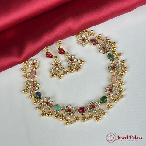 Gold necklace and earrings with gemstones on a red satin background, featuring 'Jewel Palace' logo.