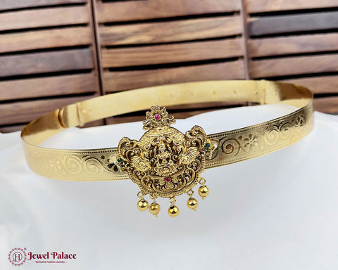 Gold headband with intricate designs and a central emblem on a white surface with wooden background