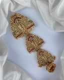 Gold bracelet with red and green gemstones on a white fabric background