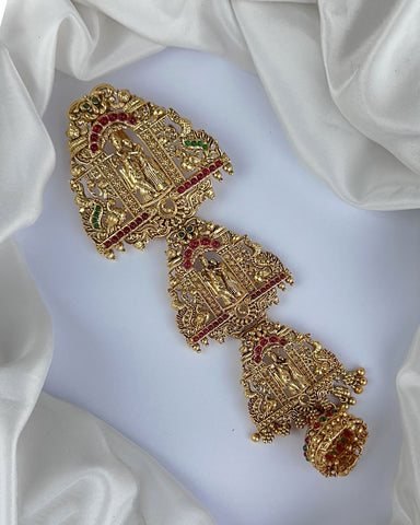Gold bracelet with red and green gemstones on a white fabric background