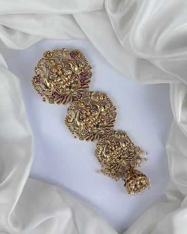 Ornate gold earrings on a white fabric background