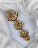 Gold earrings with intricate designs on a white fabric background