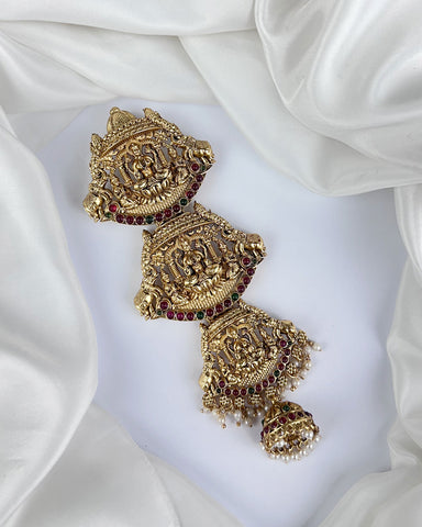 Ornate gold earrings with red stones on a white fabric background