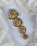 Gold jewelry piece with intricate designs on a white fabric background