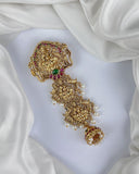 Gold necklace with intricate design and colored stones on a white fabric background