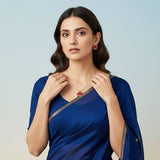 Woman wearing a blue saree with jewelry on a light background