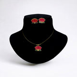 Jewelry set with red flower design on a black velvet stand against a white background