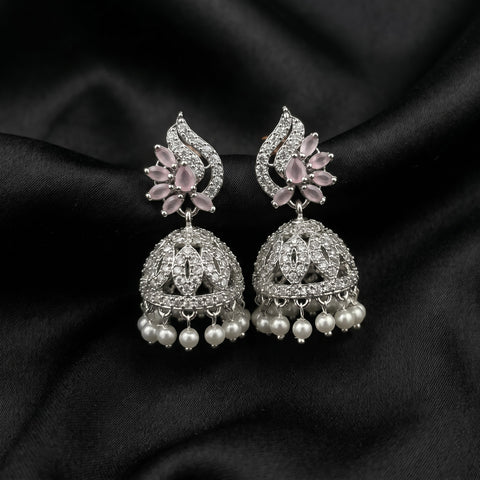 A pair of silver-toned Indian jhumka earrings with pink gemstone floral accents and dangling white pearls, displayed on a draped black satin fabric.