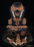 A traditional Indian jewelry set displayed on a black velvet jewelry bust and base. The set includes a statement necklace, a matching chain necklace, a large pendant, earrings, a bracelet, and a wristlet, all decorated with gold, brown, and white elements.