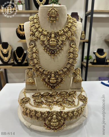A traditional South Indian bridal jewellery set displayed, including gold-plated necklaces, earrings, and hair accessories.