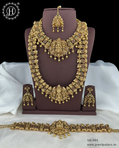 Gold necklace set on a brown stand with white fabric background