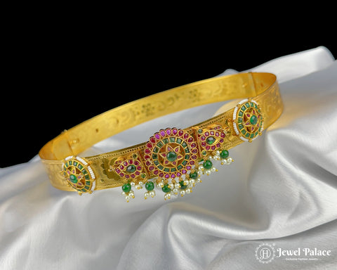 Gold headband with gemstones on a white fabric background, brand 'Jewel Palace' visible