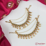 Gold necklace with green and red stones on a white fabric background, brand 'Jewel Palace' visible.