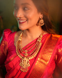 Woman wearing a red saree with gold jewelry against a warm-toned background