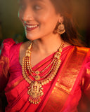 Woman wearing a red saree with gold jewelry against a blurred background