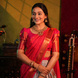 Woman in a red saree with gold jewelry against a warm-toned background