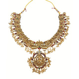 Gold necklace with intricate design and red and white stones on a white background