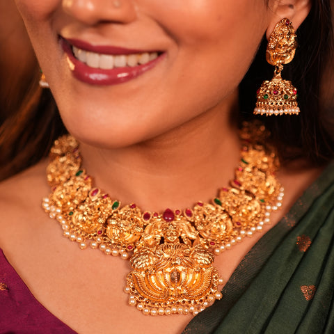 Woman wearing a gold necklace and earrings with a blurred background