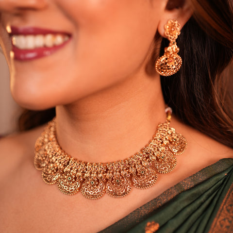 Close-up of a woman wearing gold jewelry including a necklace and earrings.