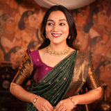 Woman in traditional attire with jewelry against a decorative wall.