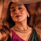 Woman wearing gold jewelry with a warm-toned background