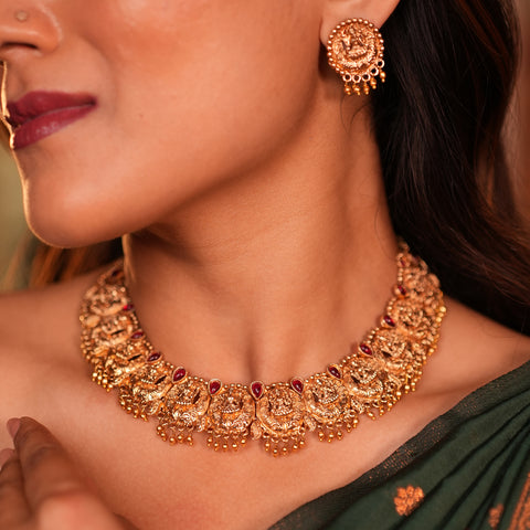 Close-up of a woman wearing a gold necklace and earrings.