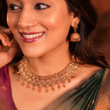 Woman wearing gold jewelry including a necklace and earrings.