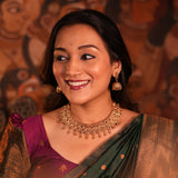 Woman wearing traditional jewelry and a saree with a decorative background