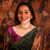 Woman in traditional attire with jewelry against a decorative background
