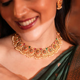 Close-up of a woman wearing a gold necklace with gemstones, smiling.