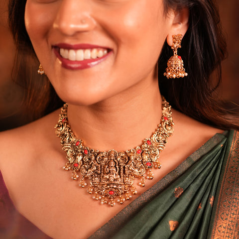 Woman wearing a gold necklace and earrings with a blurred background