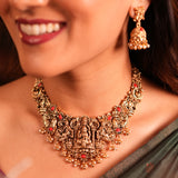 Close-up of a woman wearing an ornate gold necklace and earrings.