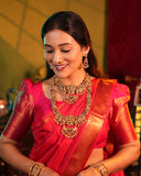 Woman in a red saree with gold jewelry against a blurred background