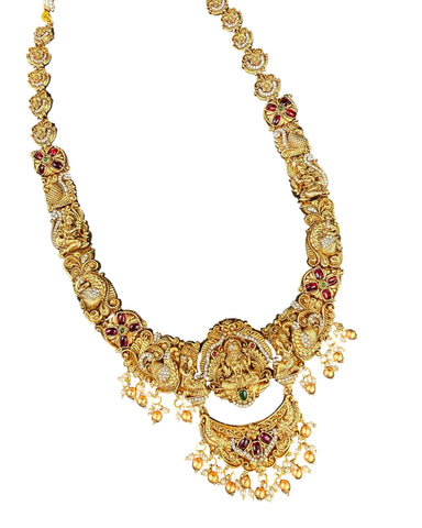 Gold necklace with intricate design and red stones on a white background