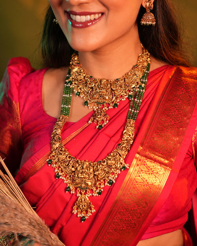 Woman wearing traditional gold jewelry and a red saree with a green background