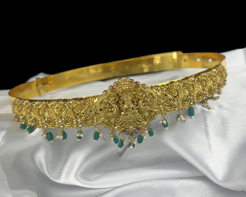 Gold headband with green gemstones on a white fabric background