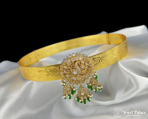 Gold headband with intricate design and green stones on a white fabric background