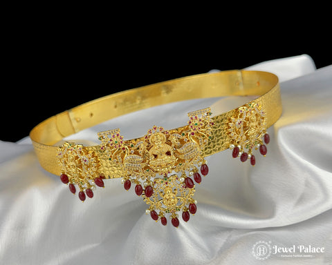 Gold necklace with red stones on a white fabric background